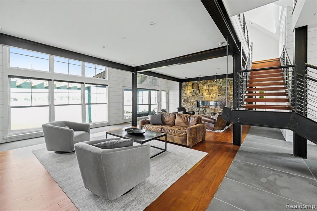 Living room with floor-to-ceiling windows, an open staircase and a fireplace