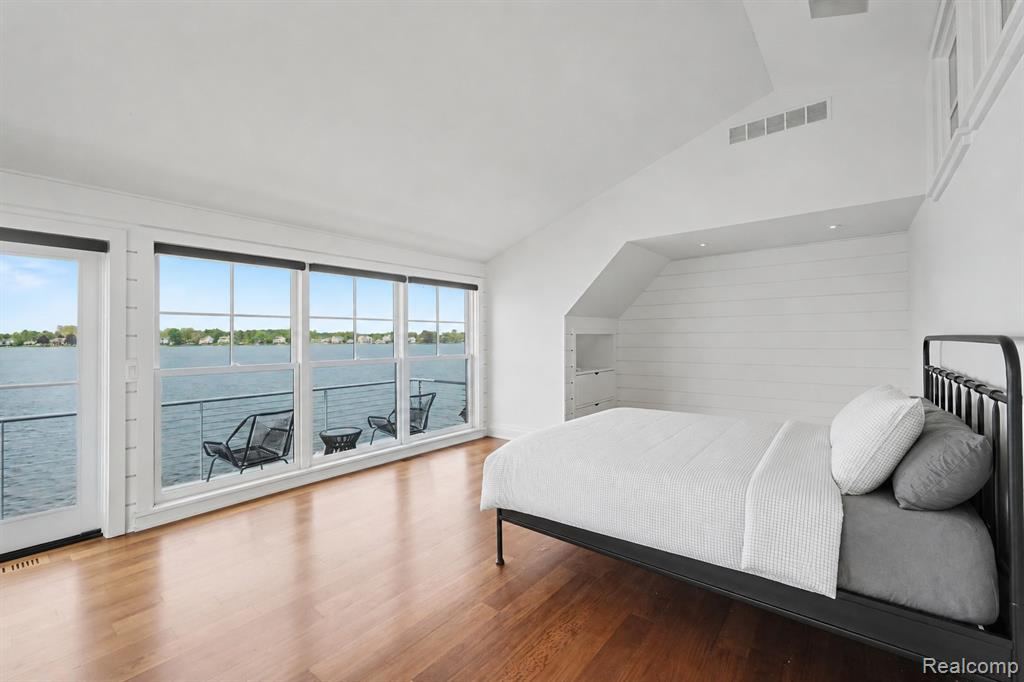Bedroom with a vaulted ceiling and a wall of windows facing the lake
