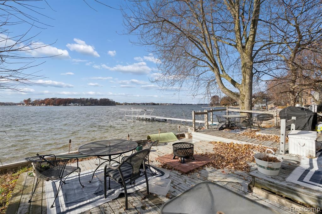 Waterfront deck with a fire pit, overlooking the boat dock and Lake Fenton