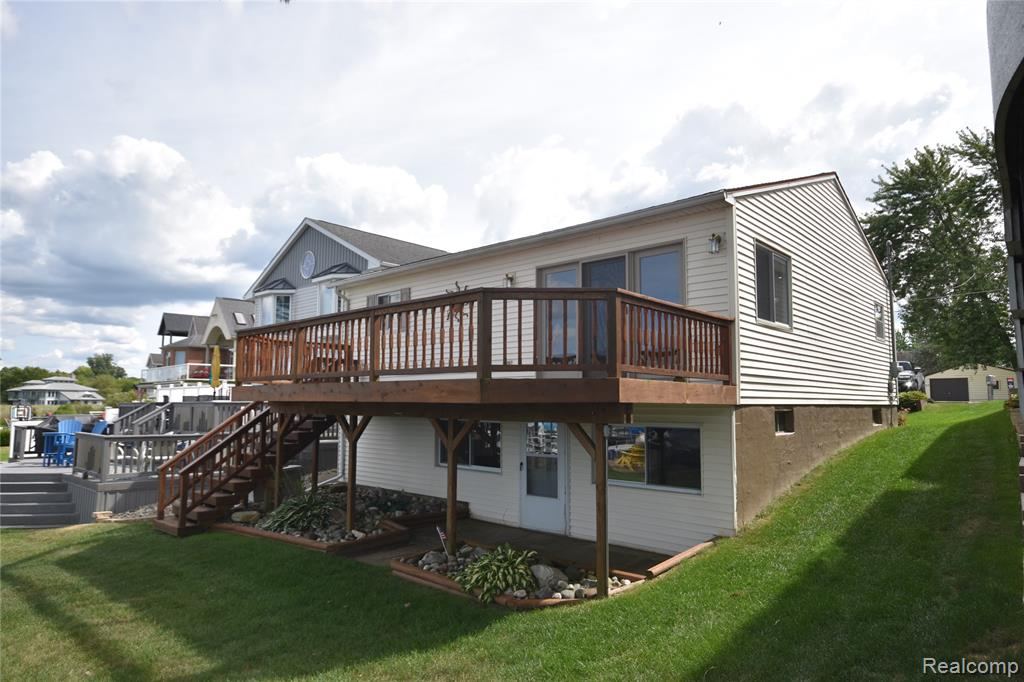 Rear of the home with a raised deck and stairway to the lawn