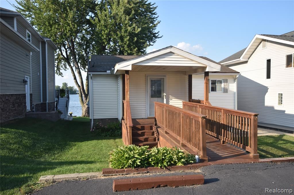 Front of the home with a shingled roof and entry deck